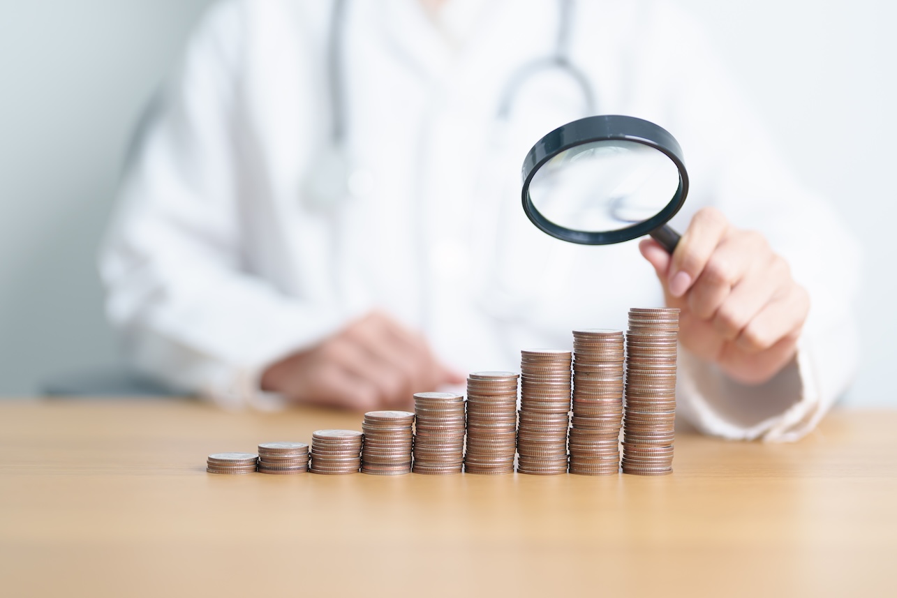 Doctor with Coins money stack growing with magnifier glass. Money saving, Job search, hiring and research development, Health Insurance, Medical, Donation and Healthcare cost concepts